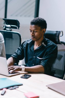 Bir grup erkek girişimci, masada otururken dizüstü bilgisayarlarla birlikte çalışırken, Afrikalı bir adam kameraya bakıp gülümserken netbook uygulaması üzerinden ödeme yapıyor.