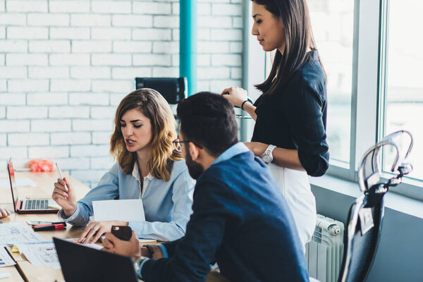 Серьёзная команда перспективных профессионалов мужского и женского пола консультирует друг друга по вопросам инноваций в финансовом мире, молодых специалистов мультикультурного бизнеса, общающихся в офисной компании
