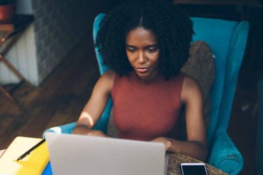 WiFi internet bağlantısı, konsantre kadın gazeteci kullanarak modern dizüstü bilgisayar üzerinde metin uygulaması için sonraki en iyi satıcı için ilginç fikirler yazarak yetenekli Afrikalı Amerikan hipster yazar