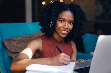 Loft iç otodidakt için zaman içinde kamera gülümseyen karanlık cilt ile mutlu kadın öğrenci portresi, neşeli Afrikalı Amerikalı kadın e öğrenme ve hazırlık ders çalışması için zevk