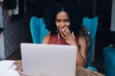 Şaşırmış koyu tenli kadın Blogger duygu heyecan, online çoklu görev kavramı dinlemek için elektronik kulaklıklar kullanarak sosyal ağlarda kendi Web sayfası hakkında alınan iyi bir video gözden