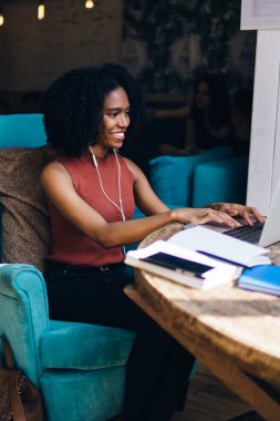 Yüksek hacimli müzik çalma listesi dinlerken Web sitesinden takipçileri ile mesajlaşma zevk neşeli kadın Blogger yan görünümü, laptop uygulaması ile iletişim kulaklıklar mutlu kadın