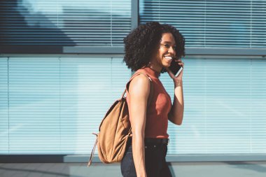 Modern akıllı telefon cihazında dolaşım internet bağlantısı kullanarak siyah Cuma sırasında iyi satın alma övünme için en iyi arkadaşa arayan elleri sırt çantası ve alışveriş torbaları ile neşeli hipster kız
