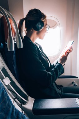 Kafkas kadın uçak yolcu okuma gemide kablosuz internet bağlı seyahat sırasında cep telefonu ile e-posta aldı, ilk iş sınıfında seyahat başarılı genç kadın. WiFi hotspot