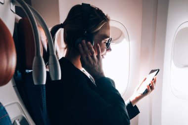 Pozitif gülümseyen iş kadını uçak ilk sınıfta seyahat ve komik video cep telefonu WiFi internet bağlı arkadaşınızın e-posta mesajı ile alınan izlerken iyi hissediyorum