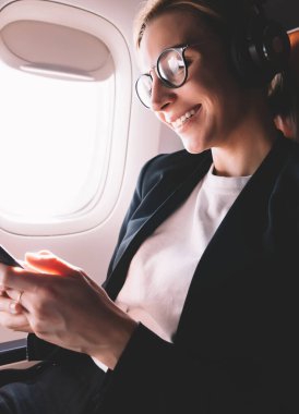 Göz giymek neşeli kadın yolcu iyi haber gemide kablosuz internet bağlı ile alınan mesaj mutlu duygu, gürültü iptali için kulaklıkta genç kadın gülümseyen