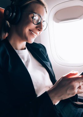 Görüntü düzeltmesi için optik gözlük neşeli kadın yolcu gemide WiFi bağlantısı kullanarak akıllı telefon uygulaması ile arkadaşlarınızla iletişimi zevk, mutlu kadın komedi film izlerken