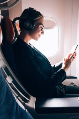 Masa içi kablosuz internet bağlantısı kullanırken resmi aşınma online olumlu video izlerken kadının yan görünümü, kulaklık üzerinden ses kaydı dinlerken kadın yolcu okuma haberleri