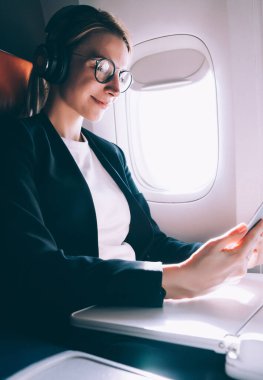 Kablosuz hotspot bağlanırken uçak, dijital tablet üzerinde kadın tarama ağı konfor uçuş sırasında online Webinar izlerken gürültü iptali için Bluetooth kulaklıklar Charming kadın