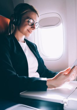 Gözlüklerde pozitif kadın, gemide iyi WiFi bağlantısı, uçak ve havayolu kavramı ile birinci sınıftaki Kıtalararası uçuş sırasında arkadaşa online görüntülü görüşme sırasında iyi hissediyor