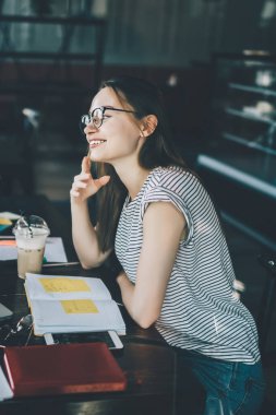 Kafede buluşup gülerken laptopları ve dersleriyle masada oturan çağdaş kadın ve erkeğin yan görüntüsü