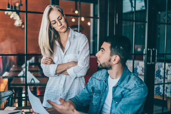 Kafede toplanırken kağıt grafikleri ve yeni fikirleri tartışan zeki kadın ve erkeğin yan görünüşü
