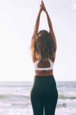 Dağ eğitimi veren kadın pozu zihni rahatlatıyor zevkten ve sakinlikten keyif alıyor. Doğada dinleniyor. Sabah Endonezya plajında egzersiz yaparken ruhsal huzur için iribaş egzersizi yapan kız.