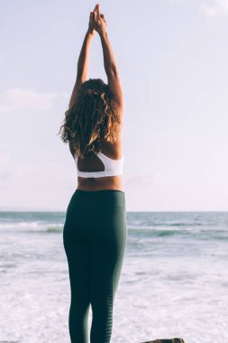 Rahatlamak için iribaş yapan genç bir kadının arka planı dikkat çeker ve konsantrasyonu keskinleştirir, kadın kıyı şeridi eğitim dengesi ve doğa üzerindeki uyum üzerine yoga yaparak zaman geçirir.