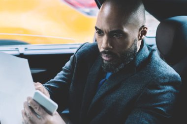 Zarif giyimli siyahi adam banliyö koltuğunda oturuyor ve şirket mali raporlarıyla uğraşarak zamanını harcıyor. Elinde kağıt tutarak strateji, iş dünyası konseptine odaklanıyor.