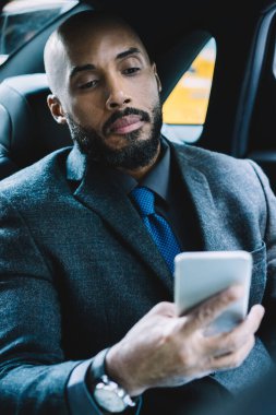 Afrika kökenli Amerikalı işadamı, lüks arabalarla ofis binasına taşınırken dijital teknolojiyi kullanıyor. Ciddi bir erkek uzman, bilgi içeren mesajlar gönderiyor.