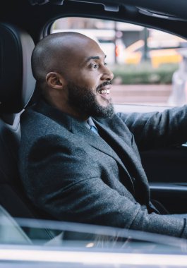 Resmi olarak başarılı olan adamın direksiyonda el ele tutuşması ve girişim toplantısına zamanında varmanın keyfini çıkarması, yeni otomobil arabasında gülümseyen olumlu erkek girişimci