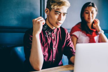 Ciddi japon adam modern kahve dükkanında kadın meslektaşı ile uzaktan çalışırken netbook için yazılım güncelleme hakkında haber okuma, Çinli erkek ve kız öğrenciler e öğrenme için zaman harcama