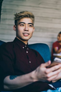 Çinli sarışın hipster adam uzaktan çalışırken ve kağıt grafik analiz ederken başlangıç projesi hakkında yeni bilgiler ile iş ortağı alınan e-posta üzerine düşünme rahat giyim giymiş