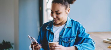 Neşeli bayan meloman grup sohbetinde arkadaşlarıyla sohbet ederken kendini iyi hissediyor. Müzik dinlemek için akıllı telefon uygulaması kullanıyor, cep telefonuyla gülümseyen hippi kız mesajlaşıyor.