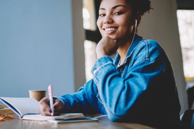 Çoklu görev ve zevk kavramı, neşeli Afro Amerikan meloman portre reklam alanında oturan ve yüksek hacimli elektronik kulaklıklar ile favori pozitif müzik çalma listesi dinleme