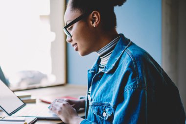 Sınav hazırlığı break sırasında web mağazasında alışveriş yapmak için kamu internet kullanarak pozitif kadın öğrenci yan görünüm, ders çalışması için bilgi arama koyu tenli yetenekli kadın