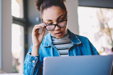 Dersler için program hakkında üniversite web sitesinde ciddi kadın öğrenci okuma makalesi, e öğrenme için yetenekli Afro Amerikan hipster kız indir dosyası ve uygulama ile üniversite muayenesine hazırlanıyor