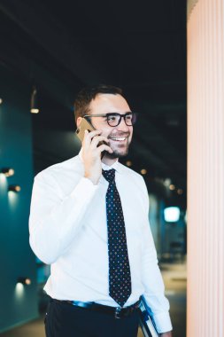 Başarılı erkek girişimci 30 'lu yaşlarda vizyon düzeltme için klasik gözlüklerle işletme bürosunda mesai günü boyunca iş arkadaşlarıyla akıllı telefon danışmanlığının keyfini çıkarıyor. Finans dünyası kavramı