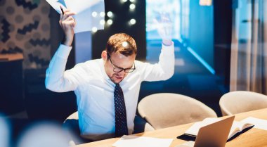 İşle ilgili sorunlar büyük borçlar ve iflas kavramı, şirketin beyaz erkek muhasebecisi kızgın hissederken masa başında oturan raporlardan elde edilen bilgileri kontrol etmeyi dene.