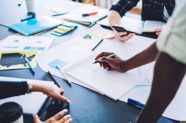 Çok ırklı kadın ve erkeklerden oluşan bir grup masa başında yeni projenin kağıt çizim planıyla ve ekip halinde tartışarak