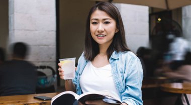 İlginç şiirler okumak için mutlu kadın erasmus öğrencisinin portresi, şehir merkezinde boş zamanlarında edebiyata düşkün kitap tutan Çinli hippi kız.