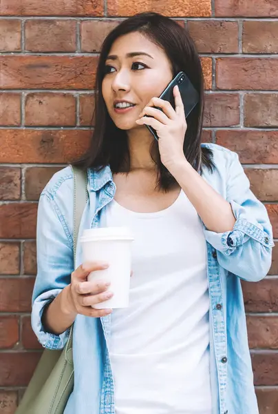 Genç bir kadın cep telefonuyla konuşuyor. Şehir duvarının arkasında duruyor. Çekici bir Çinli hippi kız, reklam metinleri için fotokopi alanının yakınlarında cep telefonu konuşması yapıyor.