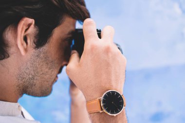 Yeni şehri keşfetmek için eski ekipmanlarla fotoğraf çeken Hintli hippi adam, şık kol saati olan genç ve yakışıklı turist tatillerde geçmişe dönük kamerayla fotoğraf çekiyor.