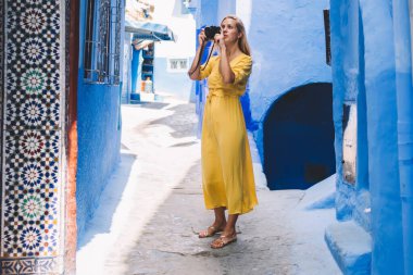 Renkli şehirde fotoğraf çeken, profesyonel kameralı güzel bir kadın - Fas 'ta yeni ekipmanlar test ediliyor, kadın fotoğrafçı tatillerde eski sokakların fotoğraflarını çekiyor.