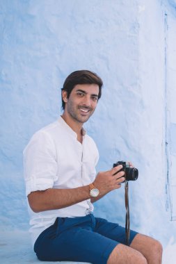 Retro kameralı yakışıklı erkek gazetecinin portresi Fas 'ı keşfettiği ve yeni makale için fotoğraf çektiği için yaz tatilinin keyfini çıkarıyor. Moda temalı kıyafet deneyleri teknolojisi olan pozitif adam.