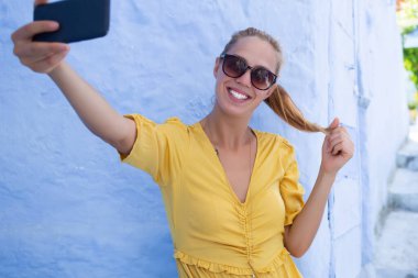 Sosyal ağda fotoğraf yayınlamak için selfie çeken neşeli kadın turist, Fas 'ı keşfeden neşeli kadın gezgin ve kendini fotoğraflıyor.