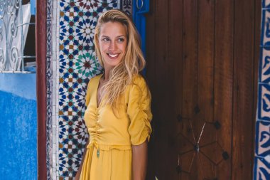 Deniz aşırı tatillerde gezen neşeli genç bayan gezgin, yabancı bir şehirde yaz macerası sırasında yabancı bir caddenin kenarındaki duvar resmi binasının yanında duran pozitif kadın gezgin Fas 'a.