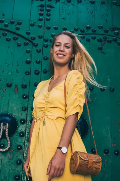 Fas 'ın tarihi merkezinde yeşil antik kapının yanında poz veren modaya uygun giyinmiş hippi bir kızın yarım boy portresi. Gezintiler sırasında gülen neşeli, kaygısız kadın.