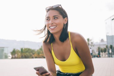 Şehir ortamında gülümseyen modern dijital cihazlı başarılı kadın blogcu e-postayla kendini iyi hissediyor. 4G kablosuz interneti cep telefonuyla kullanan gündelik kıyafetli bir kadın.