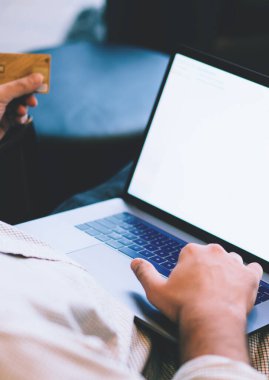 Kafkasyalı genç adamın elinde plastik kredi kartı tutarken, bankacılık verilerini doğrularken, dizüstü bilgisayardan alışveriş yaparken, web reklamları için boş ekran oluştururken yakın plan görüntüsü