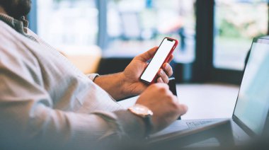 Kafkasyalı genç adamın elinde boş cep telefonu, bankacılık verilerinin doğrulanması, dizüstü bilgisayar ve cep telefonundan internet üzerinden alışveriş yapması ve web reklamları için ekran görüntüsü oluşturması.