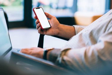 Kafkasyalı genç adamın elinde boş cep telefonu, bankacılık verilerinin doğrulanması, dizüstü bilgisayar ve cep telefonundan internet üzerinden alışveriş yapması ve web reklamları için ekran görüntüsü oluşturması.