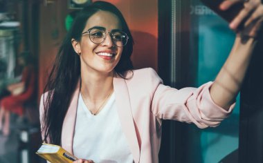 Görsel gözlüklü neşeli kadın kameraya gülümseyen ve özçekim resimlerine tıklayarak sosyal web sitesindeki takipçileri cezbetmek için göz korumasını sağlıyor. İnternet bağlantısının keyfini çıkarıyorlar.