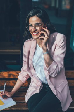 Moda gözlüklü neşeli Gürcü kadının portresi kamera planlama programına gülümserken cep telefonuyla gezen internet bağlantısı, akıllı telefondan arayan hippi kız.