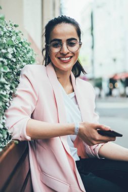 Cep telefonu aygıtındaki kablosuz bağlantıyı kullanarak sosyal ağdaki takipçilerle iletişim kurarken kameraya gülümseyen mutlu seyahat blogcusu, gezi sitesinden cevap bekleyen hippi kız
