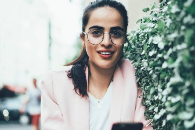 Gözlüklü çekici yeniyetme kız, seyahat gezisi sırasında internete bağlanan sosyal web sitesinde yayınlanması için isim üzerinde kafa yoruyor ve başka yere bakıyor.