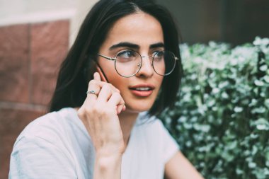 Optik gözlüklü güzel bir kadın cep telefonu ile ilgileniyor. İspanyol hippi kız dedikodu dinlerken 4G hakkında konuşmak için en iyi arkadaşına telefon ediyor.