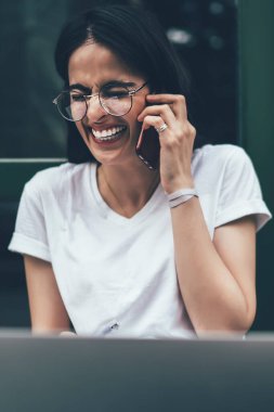 Neşeli heyecanlı İspanyol yetenekli programcı uluslararası cep telefonu konuşmaları sırasında gülüyor, neşeli yüzlü mutlu hippi kız cep telefonu aracılığıyla arkadaşlarıyla iletişim kuruyor.