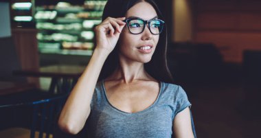 Gözlükler içinde düşünceli hipster kız bloglama hakkında profesyonel edebiyattan bilgi üzerinde durulıyor, gözlükler içinde dalgın kadın bakıyor ve en çok satan okuma için zaman hakkında düşünme