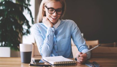 Optik gözlük mutlu kadın öğrenci üniversite kampüsünde öğrenme heyecanlı duygu, pozitif hipster kız tasarım çizimler için fikirler hakkında düşünme ders kitabında örnekler bakıyor